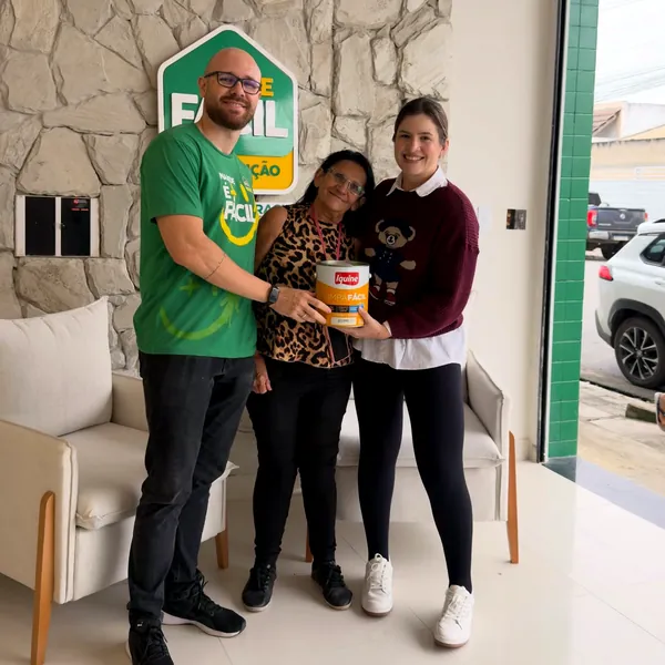 Equipe do Armazém Brasil entregando uma lata de tinta para uma cliente na loja