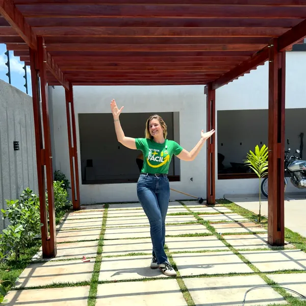 Mulher com camisa da Rede Fácil sob pergolado de madeira
